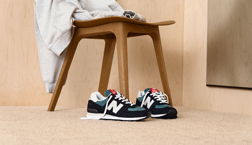 Schwarz blaue New Balance 574 neben einem Holzstuhl